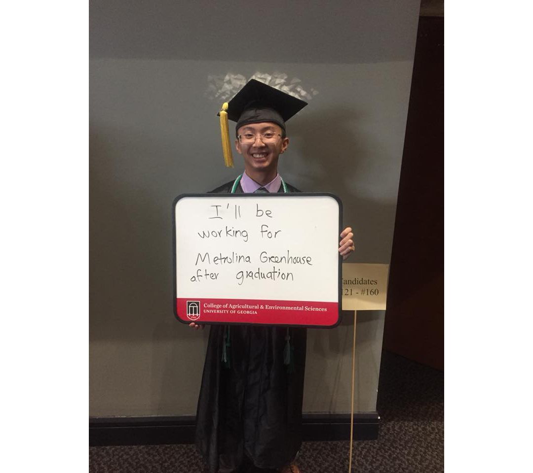 UGA graduate holds a sign that says "I'll be working for Metrolina Greenhouse"